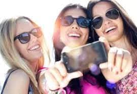 "Üç genç kadın bir arada gülerek telefonlarına bakıyor